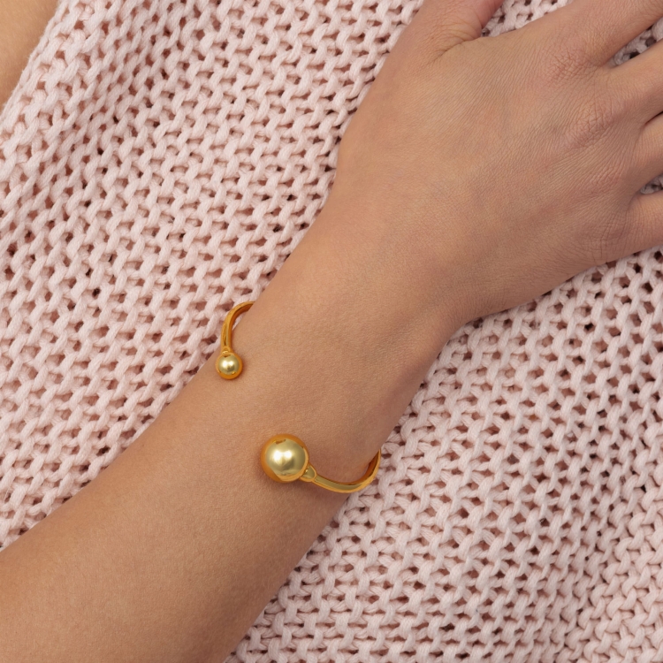 Bransoletka pozłacana sztywna zakończona dwoma kulami.